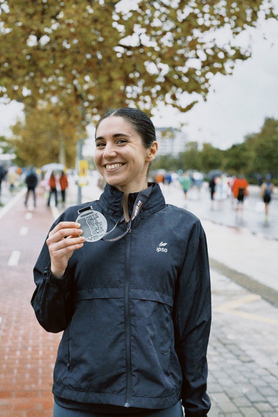Sonriendo con una medalla de finisher, de negro